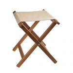 Teak folding camp stool with khaki canvas seat folded on a patio 