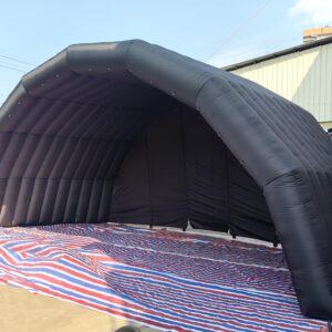 Large black inflatable stage tent set up for an outdoor event. The tent features a spacious interior, durable Oxford cloth material