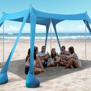 Rengue Beach Tent set up on sandy beach with 10x10ft canopy providing shade and stability, featuring sandbags and aluminum poles